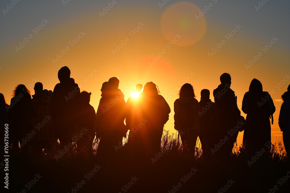 Fototapeta premium Crowd of people standing together at sunset, ideal for community, freedom, unity and inspirational concepts.