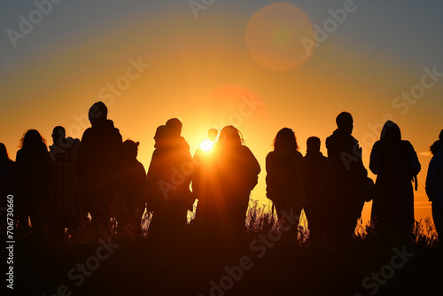 Silhouettes of people greeting the first light of the day during the spring equinox