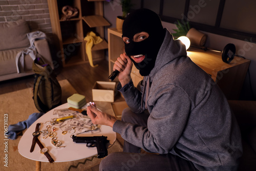 Obraz na plátně Male thief with stolen diamond ring in room at night