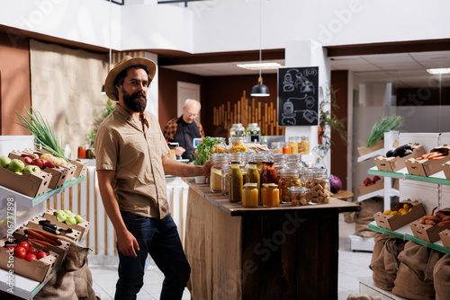 Portrait of cheerful man looking for farm grown vegetables in sustainable zero waste store. Hipster client does grocery shopping, buying chemicals free food in local neighborhood store