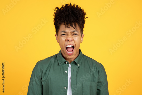 Screaming young african american man standing isolated over yellow background