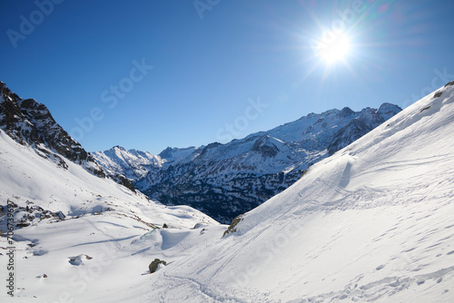 A breathtaking winter day with the sun beaming over the snow-covered expanses of the Pyrenees, near Ibon de Gorgutes, Benasque, Huesca, Spain, inviting adventure and exploration photo