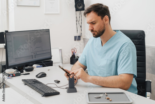 Otolaryngologist at modern medical center. Portrait of audiologist who assess disorders of hearing working with smartphone and computer. Copy space photo