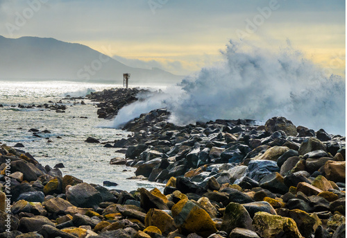 Fotografie High surf waves crashing over breakwater