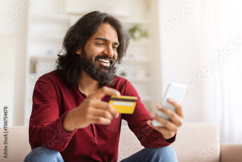 Positive indian guy enjoying newest shopping application