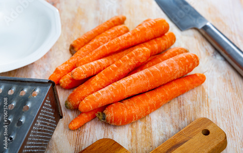Raw unpeeled carrots on wooden table, ingredients for cooking at home