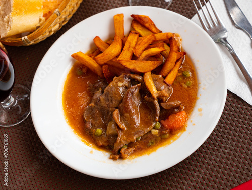 Hearty dinner of pieces of boneless veal stewed in gravy served with vegetable side dish of fried potatoes