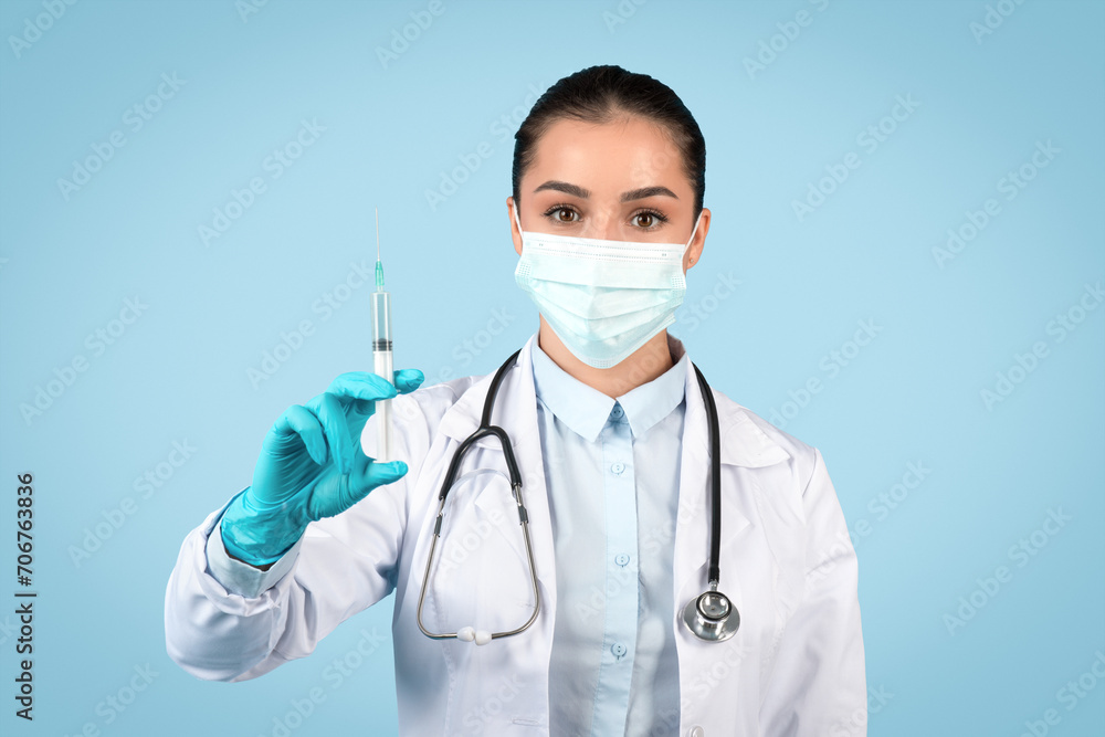 Woman doctor in protective mask holding a syringe Woman doctor in protective mask holding a syringe