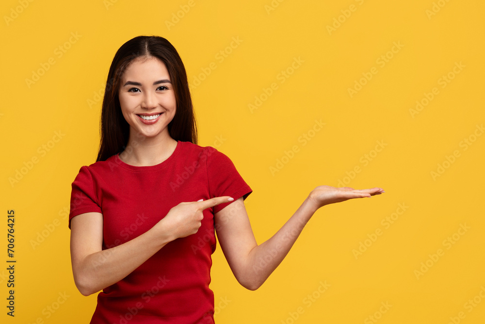 Cheerful asian woman pointing at copy space on her palm Cheerful asian woman pointing at copy space on her palm