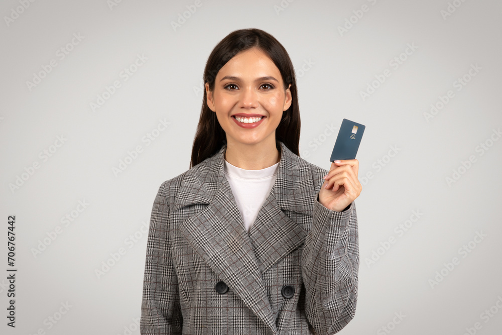 Cheerful woman holding a credit card, smiling at camera Cheerful woman holding a credit card, smiling at camera