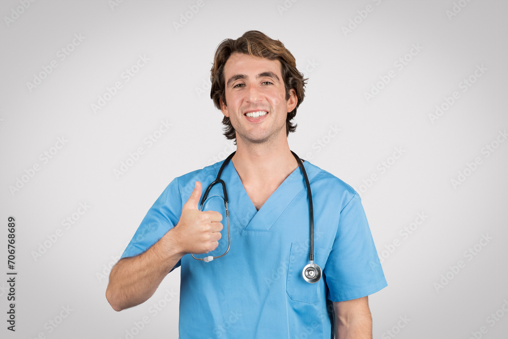 Smiling european man nurse giving thumbs up on grey background Smiling european man nurse giving thumbs up on grey background