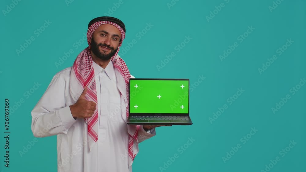 Muslim adult shows greenscreen laptop with blank mockup layout on ...