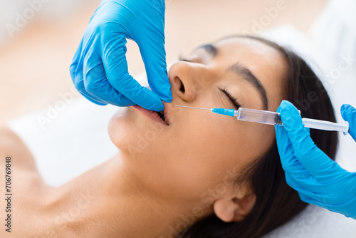 Beautician hands making beauty lips injection for beautiful young woman photo