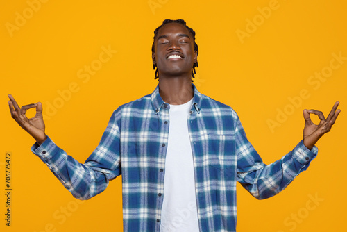 Zen. Relaxed young black man in plaid shirt meditating with eyes closed