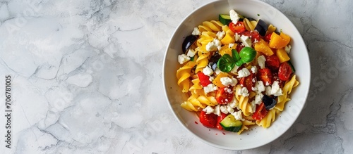 pasta salad with grilled vegetables zucchini eggplant bell pepper ant tomato and feta cheese on white bowl top view. with copy space image. Place for adding text or design photo