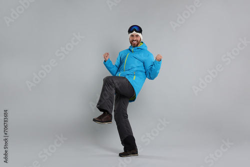 Winter sports. Cheerful man in ski suit and goggles on gray background photo