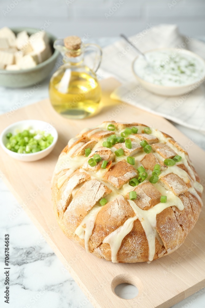 Freshly baked bread with tofu cheese and green onion on white marble table