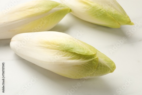 Raw ripe chicories on white marble table, closeup