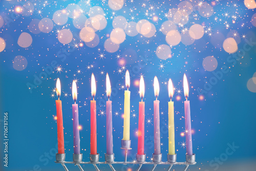 Hanukkah celebration. Menorah with burning candles on blue background with blurred lights  closeup
