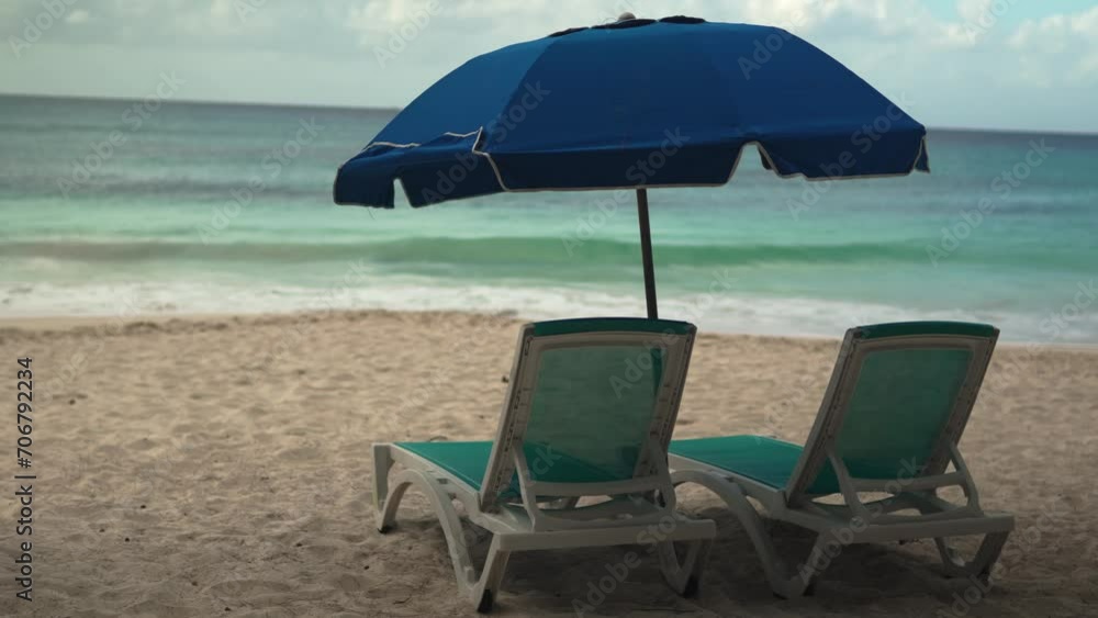 A tranquil beach setup with two empty chairs and an umbrella, invitingly facing the serene ocean. Perfect for depicting quiet, relaxing getaways A tranquil beach setup with two empty chairs and an umbrella, invitingly facing the serene ocean. Perfect for depicting quiet, relaxing getaways