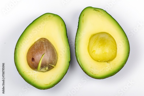 An avocado, cut in half, is displayed on a white surface, showcasing its green texture.