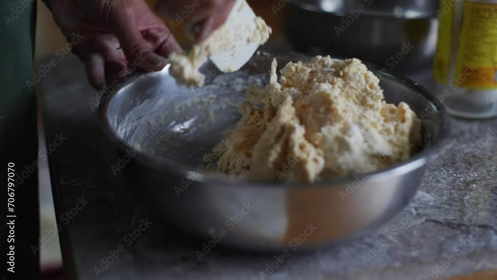 Raw dough ingredients mixed using baking spoon in steel bowl on kitchen tabletop, filmed as closeup handheld slow motion shot Raw dough ingredients mixed using baking spoon in steel bowl on kitchen tabletop, filmed as closeup handheld slow motion shot