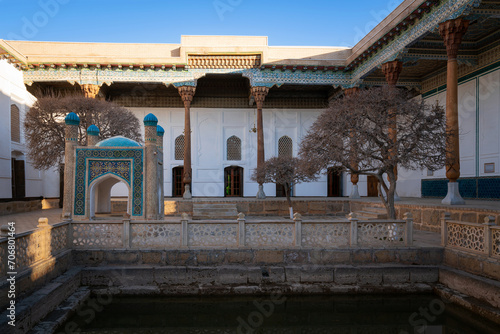 View of the courtyard of the Bahauddin Naqshbandi Memorial Complex with a pond and a chartak in the foreground on a sunny day, Bukhara, Uzbekistan photo