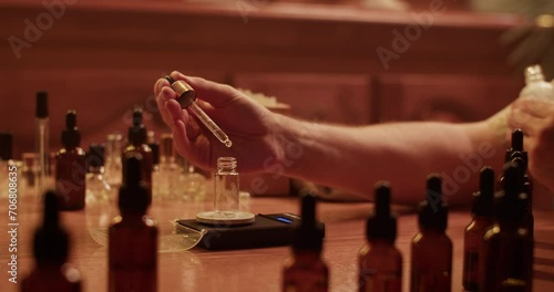 Cropped perfumer measuring weight of oil drop