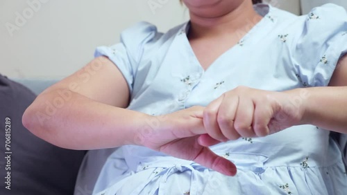 A pregnant woman putting pressure on her right arm by squeezing and pressing them down while she is sitting on her couch in the living room. photo