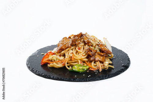 fried noodles with vegetables and meat in a flat plate on a white background, side view