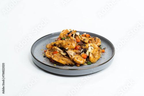 fried Asian dish with sweet and sour sauce, garlic and vegetables on a plate, side view