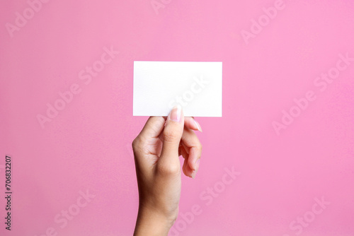 White blank card for mockup in woman hand isolated on a pink background photo