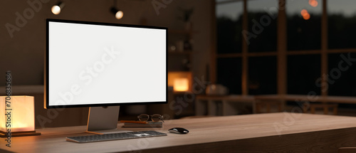 A PC computer mockup on a hardwood table in a cosy, modern room at night. dark workspace concept photo