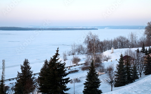 active people walk along the embankment of the Volga river and on frozen ice on a winter evening
