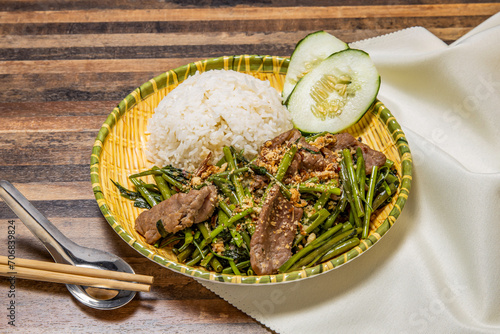 Belacan Water Spinach and beef with Rice with cucumber and chopsticks served in dish isolated on wooden table top view of hong kong fast food