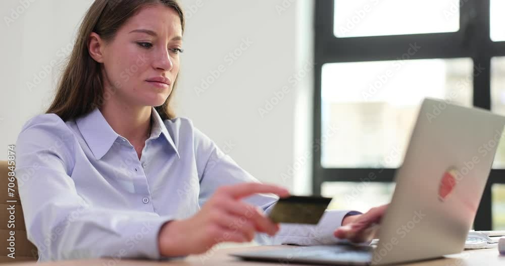 Young woman enters data on laptop keyboard holding bank card Young woman enters data on laptop keyboard holding bank card