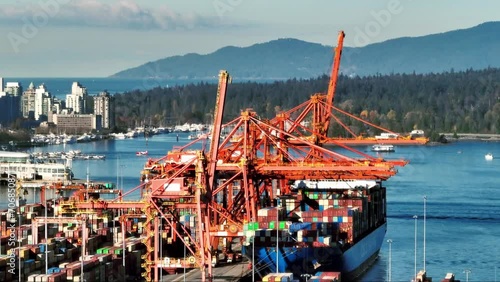 Port Crane Unloading Containers From Ship Docked At The Terminal. GCT Vanterm In Vancouver, BC, Canada. aerial sideways shot photo