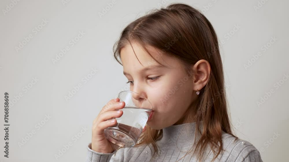 Little girl drinks water from a glass, white background Little girl drinks water from a glass, white background