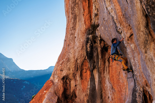 rock climber on a rock. Athletic man climbing up an overhanging rock with a rope.