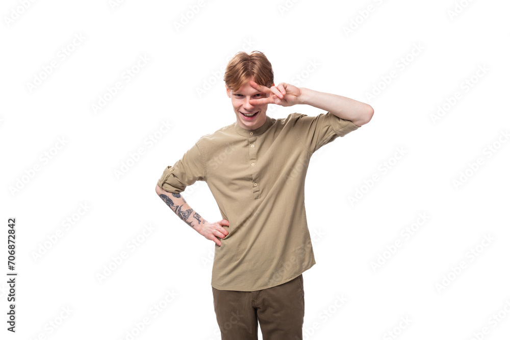 young cheerful caucasian man with red hair is dressed in a khaki shirt and brown trousers young cheerful caucasian man with red hair is dressed in a khaki shirt and brown trousers