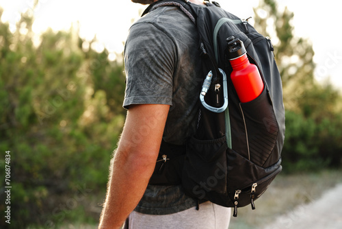 A male traveler backpack with mountaineering carabiner and thermos close up photo