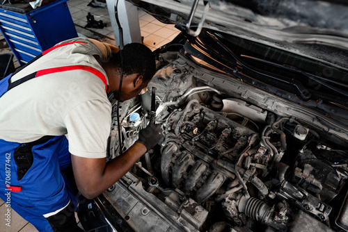 Young African auto mechanic checking car engine under the hood in auto service © fotofabrika