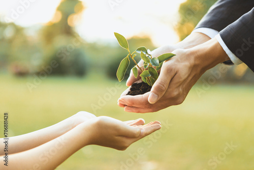 Businessman handing plant or sprout to young boy as eco company committed to corporate social responsible, reduce CO2 emission and embrace ESG principle for sustainable future.Gyre