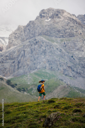 boy with a backpack on a hike against the backdrop of the mountains. child traveler with backpack, hiking, travel, mountains in the background, kids summer vacation.