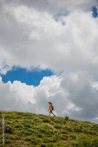 boy goes with a backpack against the backdrop of clouds in the mountains. child traveler with backpack, hiking, lifestyle concept