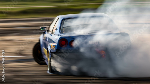 Blurred car drifting diffusion race drift car with lots of smoke from burning tires on speed track, Professional driver drifting car on race track with smoke. © Darunrat