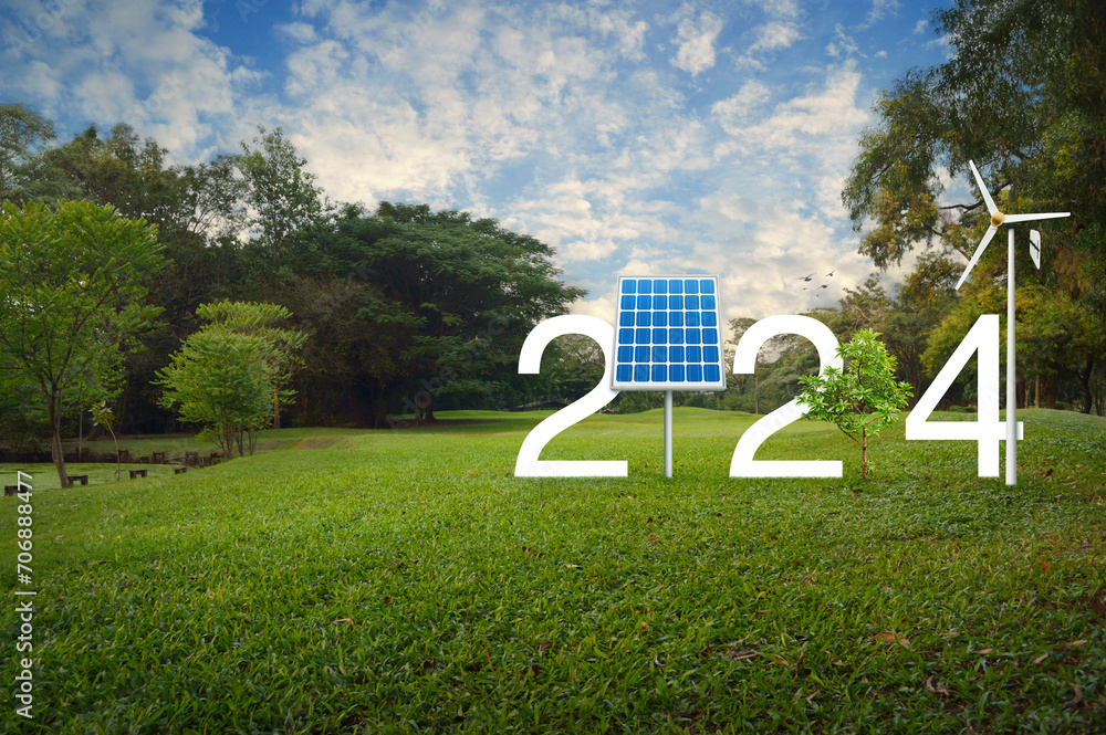 Fototapeta premium 2024 white text with solar cell, wind turbine and growing tree on green grass field in park, Happy new year 2024 ecological cover concept