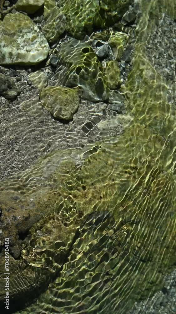 Sunlight effects on the ground of a mountain stream in summer, vertical shot Sunlight effects on the ground of a mountain stream in summer, vertical shot