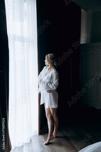 Morning of the bride, where she gets ready for a wedding in a beautiful luxury hotel in a robe with stylish hair and makeup, and then puts on a white wedding dress.