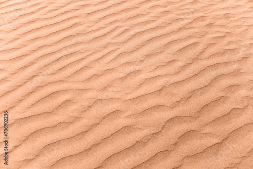 closeup of sand pattern of a beach in the summer. New trending PANTONE Peach Fuzz colour of 2024 year